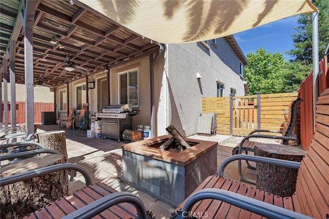 wooden deck featuring a fire pit, a patio, fence, and a grill