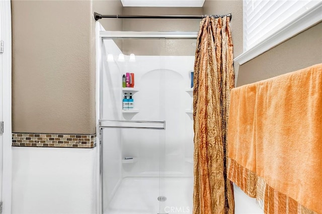 bathroom featuring a textured wall and a stall shower