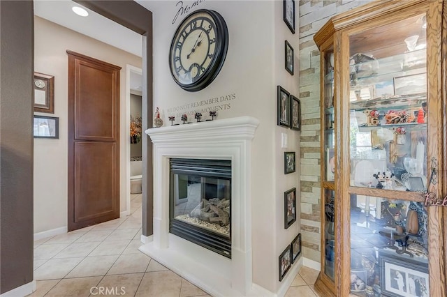 interior space featuring a glass covered fireplace and baseboards