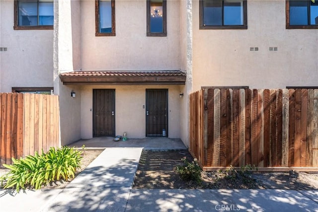 view of front of property featuring a tiled roof, fence, and stucco siding