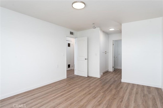 spare room featuring visible vents, light wood finished floors, and baseboards