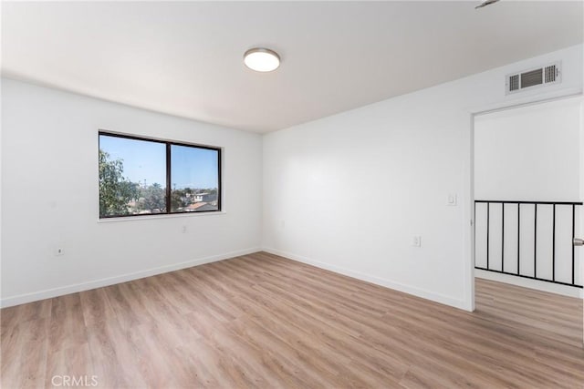 unfurnished room with light wood-style flooring, visible vents, and baseboards