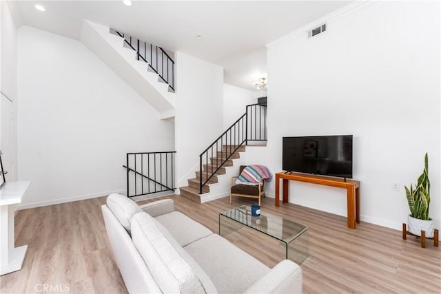 living area with stairway, baseboards, visible vents, and wood finished floors