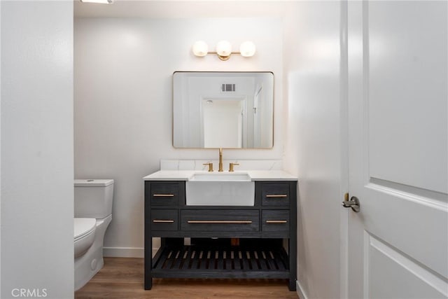 bathroom featuring toilet, wood finished floors, visible vents, vanity, and baseboards