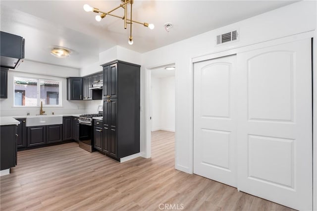 kitchen with light countertops, visible vents, light wood-style floors, a sink, and stainless steel gas range oven