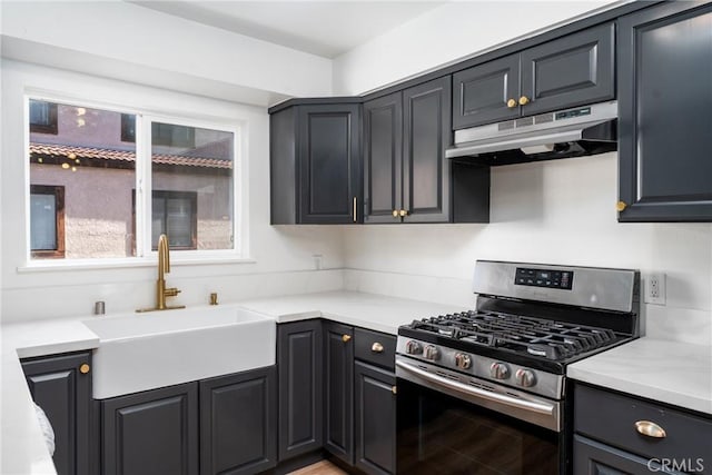 kitchen featuring gas stove, light countertops, a sink, and under cabinet range hood