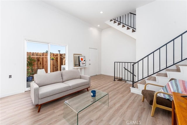 living room featuring recessed lighting, a high ceiling, wood finished floors, baseboards, and stairs