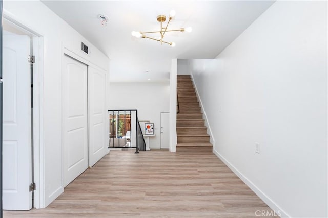 stairway featuring baseboards, visible vents, a notable chandelier, and wood finished floors