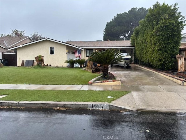 view of front facade with a front yard, concrete driveway, and stucco siding