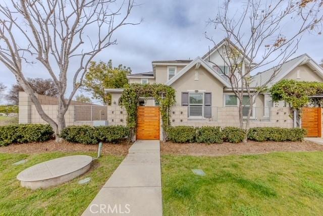 view of front of property featuring a front lawn, fence, and stucco siding