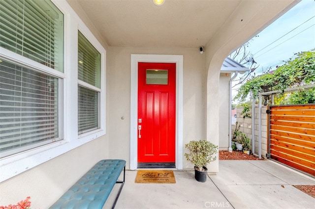 entrance to property featuring fence and stucco siding