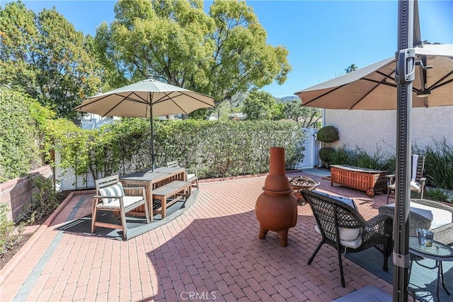 view of patio featuring outdoor dining area, a fenced backyard, and a fire pit