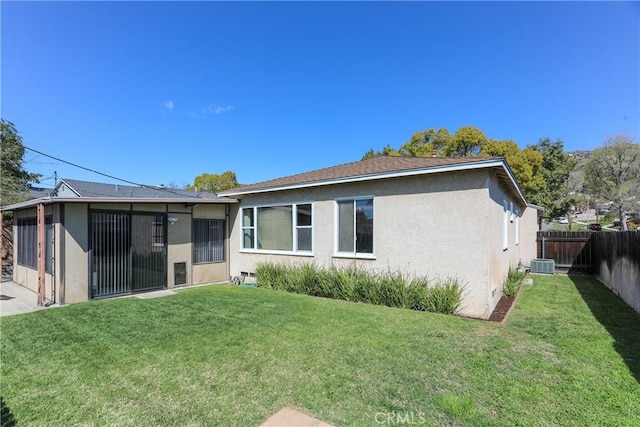 rear view of property with a fenced backyard, central AC unit, a lawn, and stucco siding