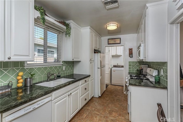 kitchen with washer / dryer, tasteful backsplash, white appliances, white cabinets, and a sink