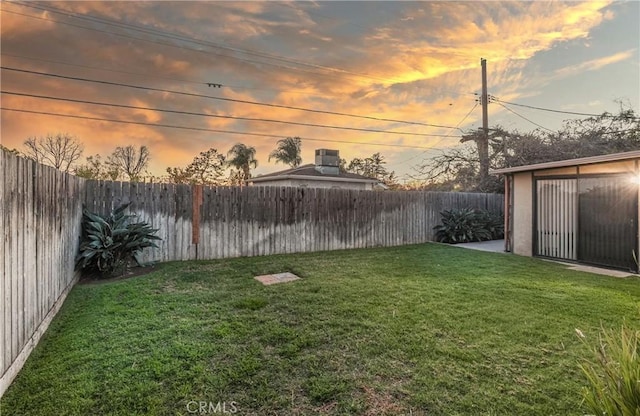 yard at dusk featuring a fenced backyard