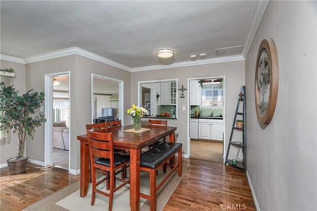 dining area featuring ornamental molding, plenty of natural light, baseboards, and wood finished floors