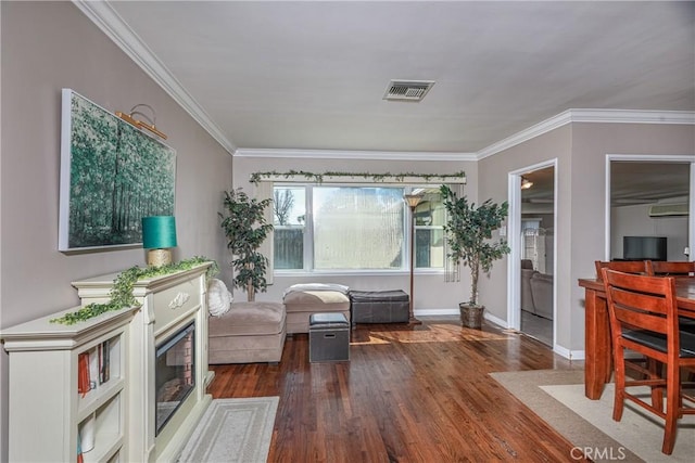 sitting room featuring baseboards, crown molding, visible vents, and wood finished floors