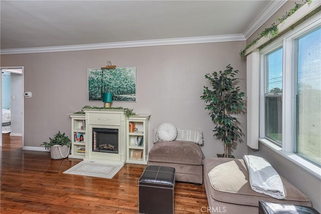 living room featuring a fireplace with raised hearth, ornamental molding, and wood finished floors