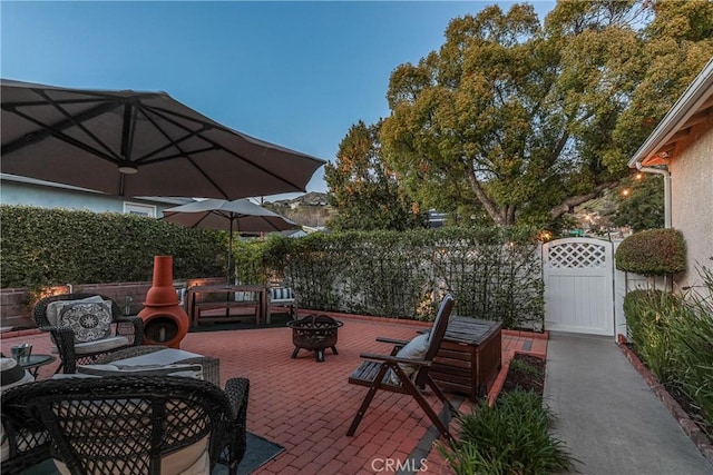 view of patio with an outdoor fire pit, a gate, and fence