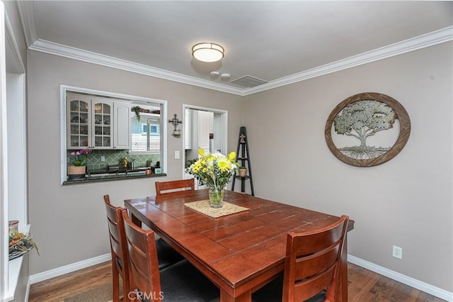 dining area featuring ornamental molding, dark wood-style flooring, and baseboards