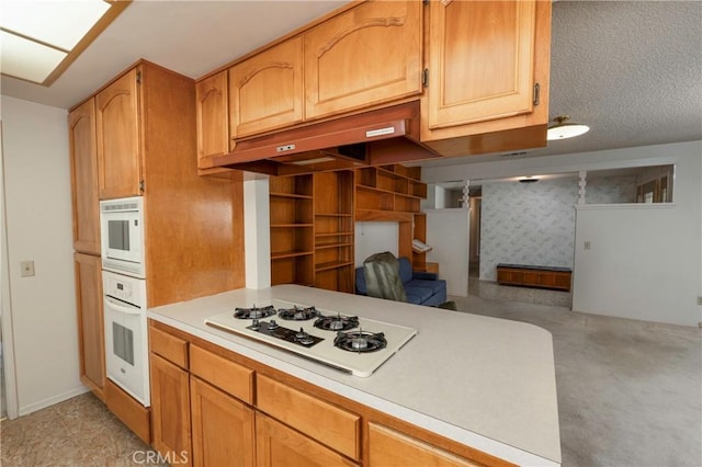 kitchen with white appliances, a peninsula, light countertops, a textured ceiling, and open floor plan