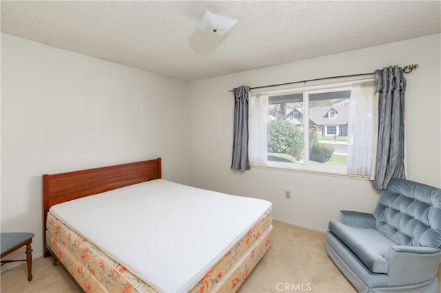 bedroom featuring light colored carpet and a textured ceiling