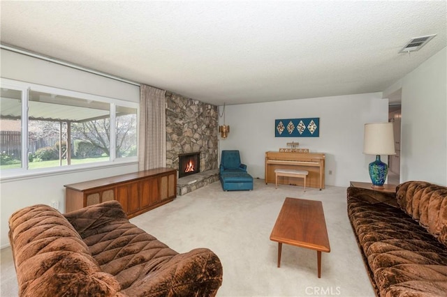 carpeted living room with a stone fireplace, visible vents, and a textured ceiling