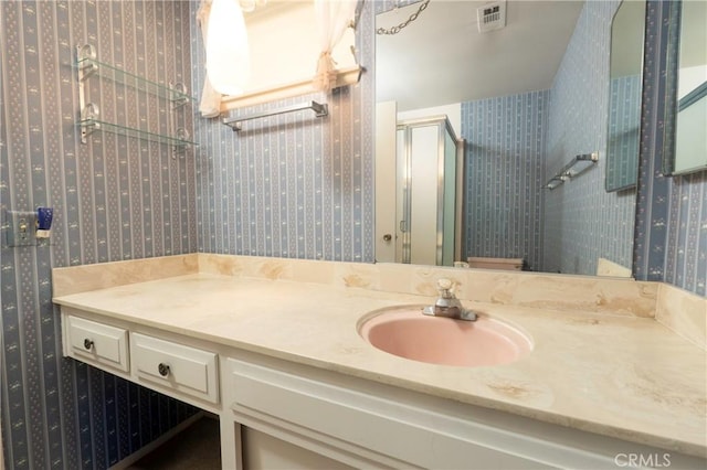 full bath with vanity, a shower stall, visible vents, and wallpapered walls