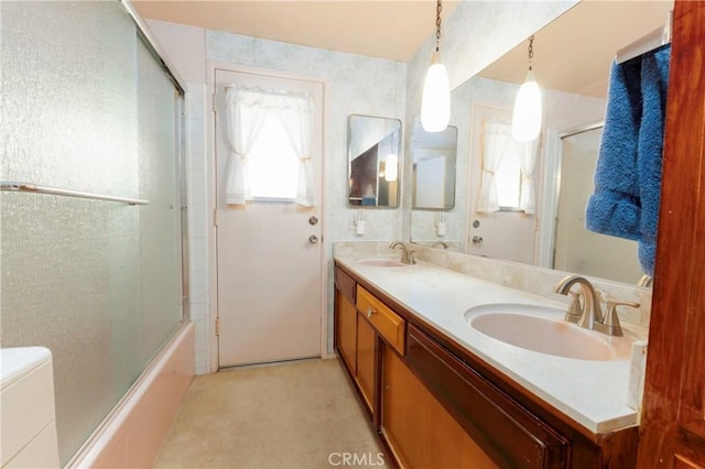 full bathroom with enclosed tub / shower combo, double vanity, and a sink