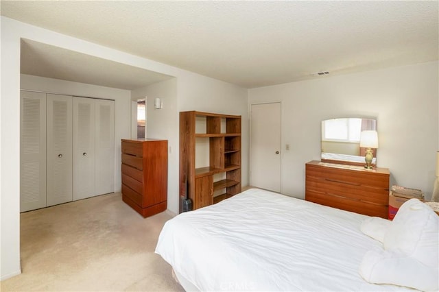 carpeted bedroom with visible vents, a closet, and a textured ceiling