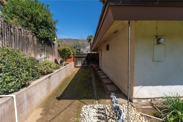 view of side of property featuring fence, a mountain view, and stucco siding