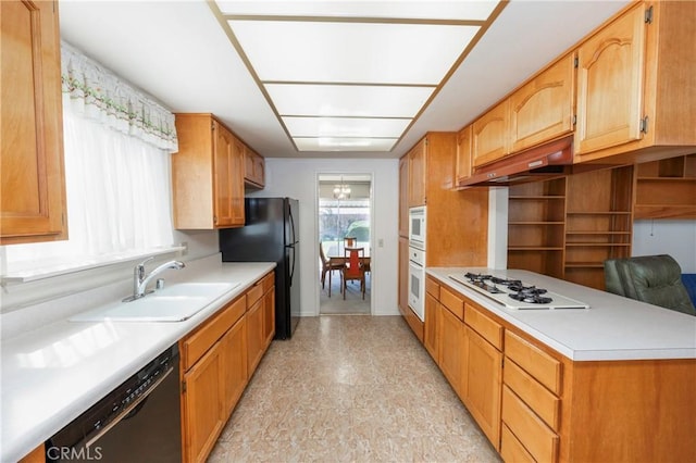 kitchen with a sink, black appliances, under cabinet range hood, and light countertops