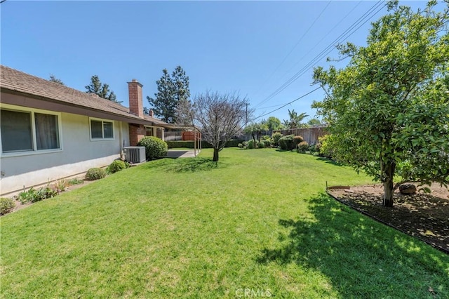 view of yard featuring fence and central AC