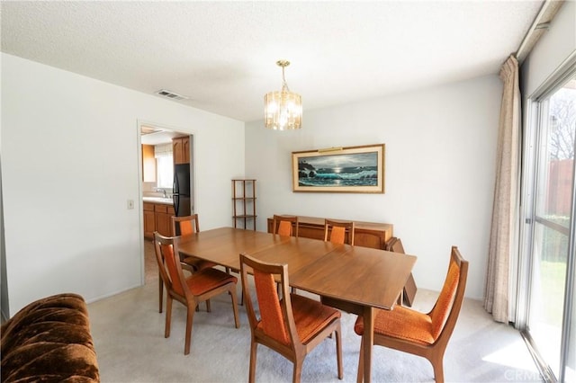 dining area with a textured ceiling, visible vents, light colored carpet, and a notable chandelier