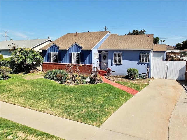 view of front of home featuring concrete driveway, roof with shingles, fence, a front lawn, and stucco siding