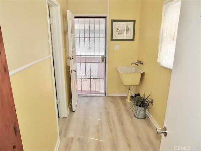 doorway with baseboards and wood finished floors