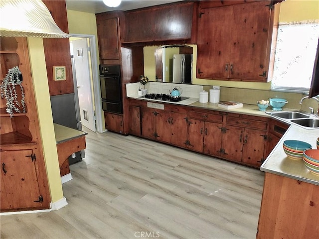 kitchen featuring light wood-type flooring, black appliances, light countertops, and a sink