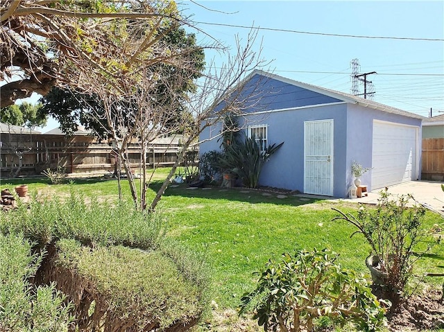 view of yard featuring an outbuilding, driveway, fence, and a garage