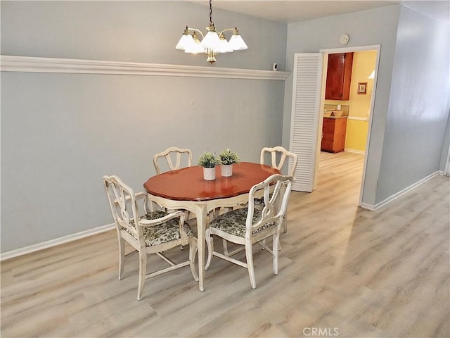 dining space featuring a chandelier, baseboards, and light wood finished floors