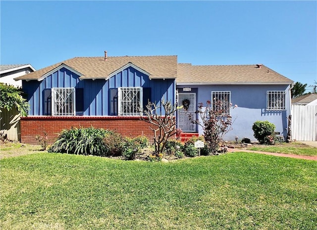 view of front of property with board and batten siding, a front yard, and brick siding