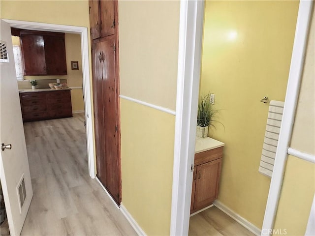 corridor with baseboards, visible vents, and light wood-style floors