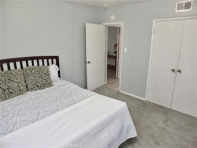 carpeted bedroom featuring a closet and visible vents