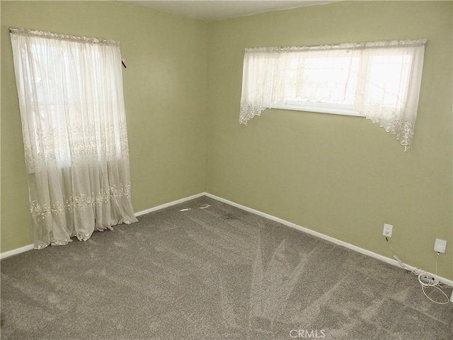 carpeted empty room featuring baseboards