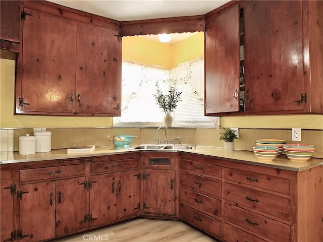 kitchen featuring brown cabinets, light wood-style floors, light countertops, and a sink