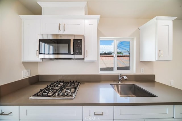 kitchen featuring dark countertops, appliances with stainless steel finishes, white cabinets, and a sink