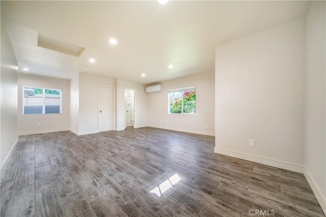 unfurnished room featuring plenty of natural light, baseboards, wood finished floors, and a wall mounted air conditioner