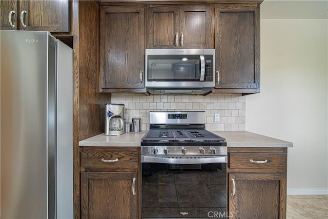 kitchen with dark brown cabinetry, stainless steel appliances, decorative backsplash, and light countertops