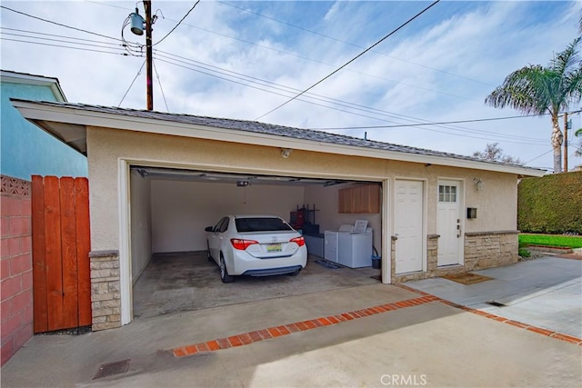 garage with driveway, fence, and washer and dryer