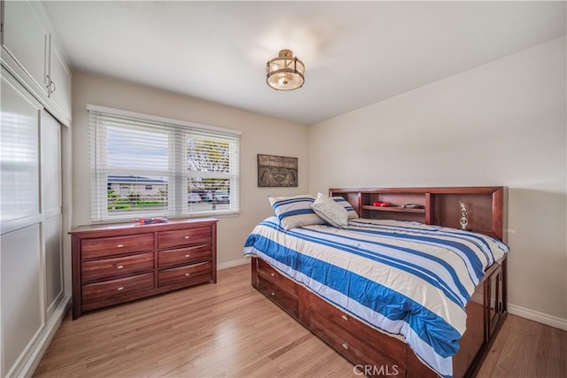 bedroom featuring a closet, baseboards, and light wood finished floors