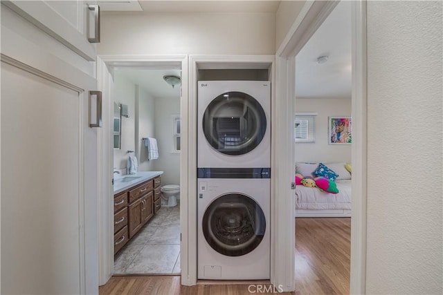 laundry room featuring light wood-type flooring, laundry area, and stacked washing maching and dryer